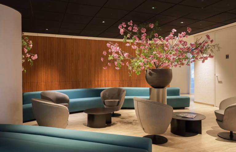 Wachtkamer met stoelen, blauwe bank en sierbloemen