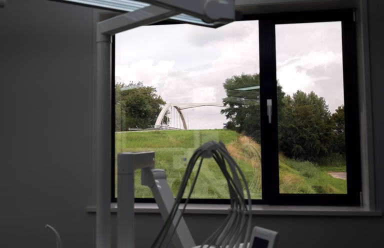 Behandelkamer met een raam en in de verte een witte brug